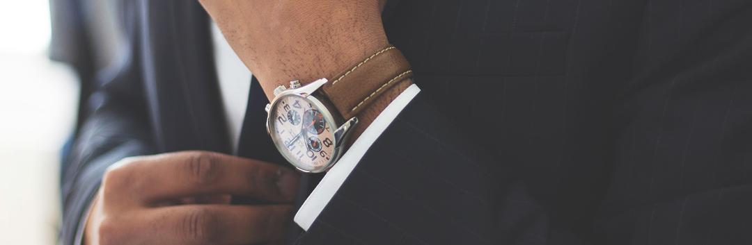hand adjusting watch on wrist of a man in suit