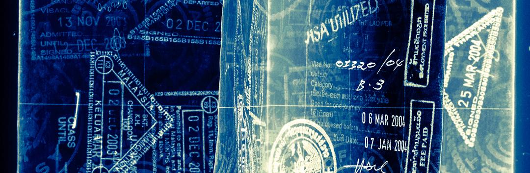 A close-up of passport pages shows various visa stamps and entry dates, including visible stamps from the United States and other countries, in shades of blue and white.