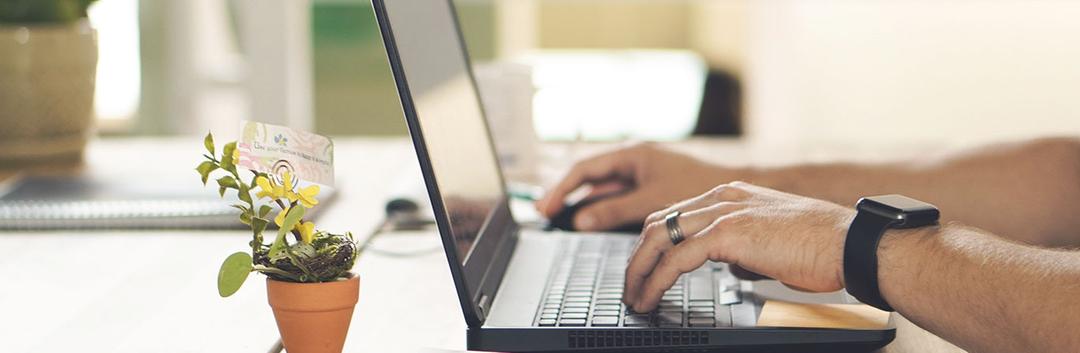 Hands working on a laptop at a working desk